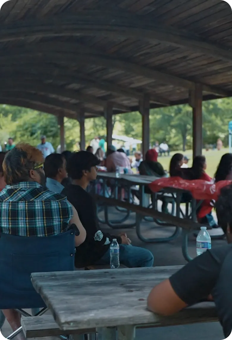 Comfort Home Care Community Event at a Local Park | Comfort Home Care Community event attendees seated at picnic tables under an outdoor park pavilion