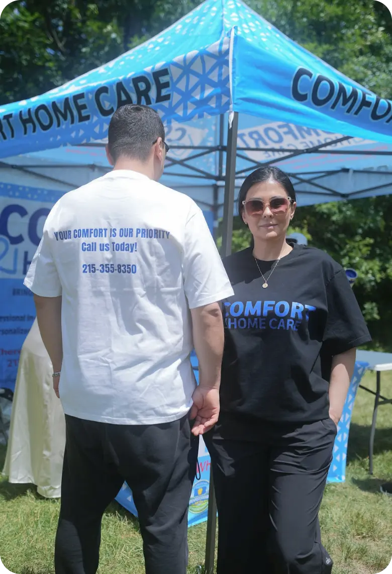 Comfort Home Care Team at a Community Outreach Event | Comfort Home Care Comfort Home Care team members standing in front of a branded community outreach booth